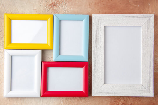 Close up view of small and big colorful photo frames hanging on nude color wall with free space