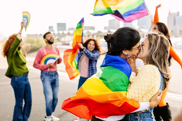 Fototapeta premium Lesbian couple kissing on LGBTQ parade festival. Two young girlfriends in love. Diverse people of gay and lesbian community celebrating lgbt pride day