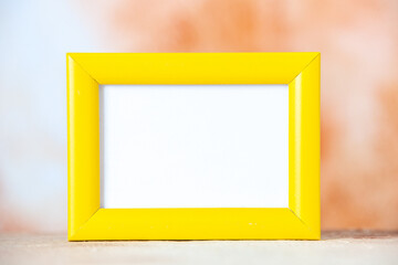 Close up view of yellow empty picture frame standing on table on colorful background with free space