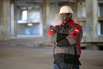 African american worker stands at construction area and looks at camera