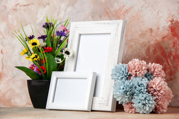 Front close view of white small big empty wooden photo frames and beautiful flowers on mixed colors background