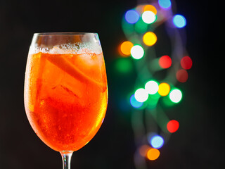 Glass of Aperol Spritz cocktail on a blurred background with colorful bokeh. Aperol spritz...