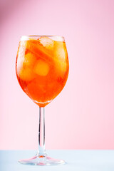 Aperol Spritz cocktail in glass on a pink blue background. Cocktail Aperol Spritz with orange and ice cubes. Close up