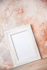 Front view of empty white wooden photo frame hanging on nude colors wall in the wrong form with free space