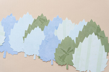 overlapping machine-cut lobed scrapbook paper leaves with serrated edges on old beige art paper