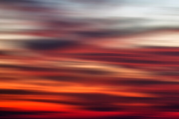 Background of the motion blurry red, white and black clouds under the beautiful sunset sky. Clouds exert numerous influences on Earth's troposphere and climate.