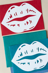 two oversized lips that have been machine-cut from scrapbook paper on red and green blue paper cards