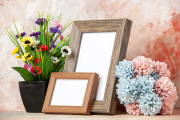 Side view of dark brown empty wooden photo frames and beautiful flowers on mixed colors background