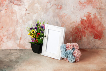 Top view of white empty wooden photo frame and beautiful flowers on mixed colors background