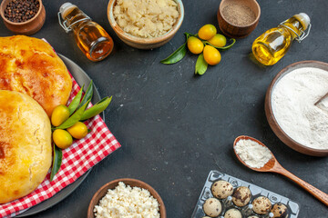 Top view of delicous fresh baked pastries kumquats with stem on red stripped towel and cheese peppers fallen oil bottles flour in a brown pot on dark blackground