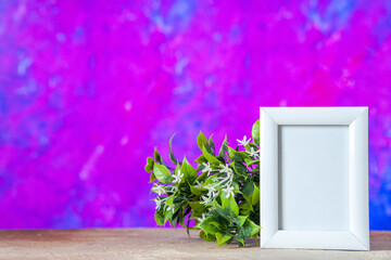 Top view of empty picture frame standing on table and flower pot