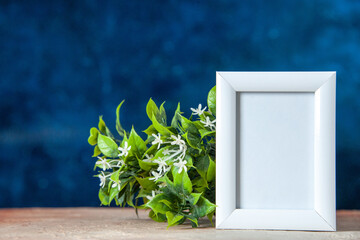 Top view of empty picture frame standing on table and flower pot on sky blue background
