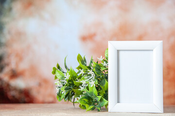 Top view of empty picture frame standing on table and flower pot on soft color background