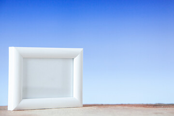 Top view of empty picture frame standing on table on blue white mix color background with free space