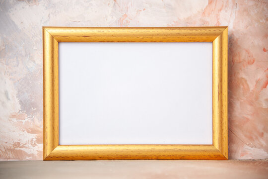 Top view of golden photo frame hanging on soft color wall with free space
