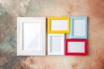 Top view of small and big colorful picture frames hanging on nude color wall with free space