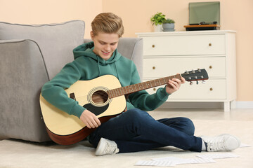 Teenage boy playing acoustic guitar in room