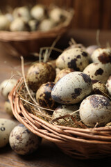 Wicker bowl with quail eggs and straw on table, closeup