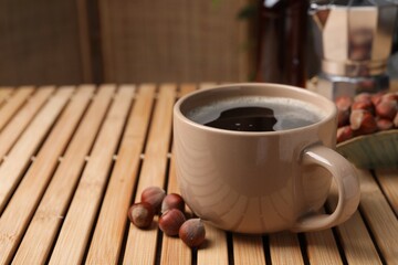Mug of aromatic coffee with hazelnut syrup on wooden table, closeup. Space for text