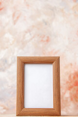 Vertical view of empty free brown photo frame hanging on pastel color wall with free space