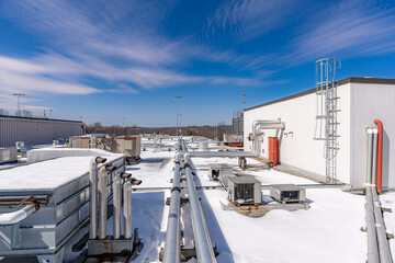Photo of a roof exhaust ventilation and piping equipment on a snow covered commercial building - Powered by Adobe