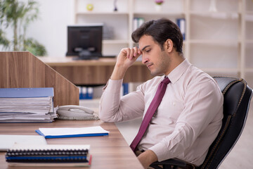 Young male employee and too much work in the office