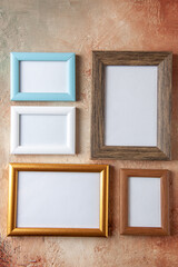 Vertical view of wooden photo frames in different sizes hung on side by side on mix color wall with free space