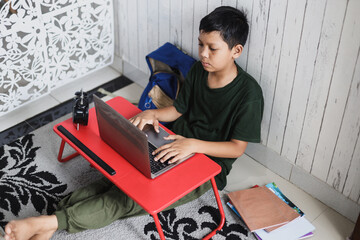 Distance learning online education. A schoolboy boy studies at home and does school homework.