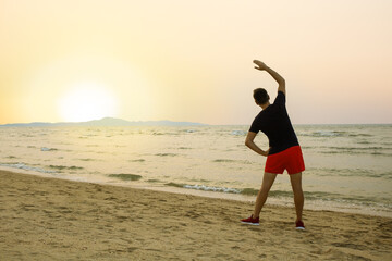 sportsman man in sport clothes warm up training do stretch exercise on sand sea ocean beach outdoor.