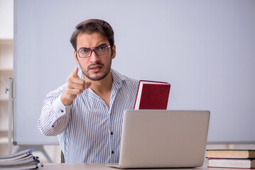 Young male teacher sitting in the classroom