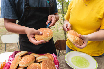 An Unrecognizable Young Latin Man preparing bread for cheeseburger with His Beloved girlfriend