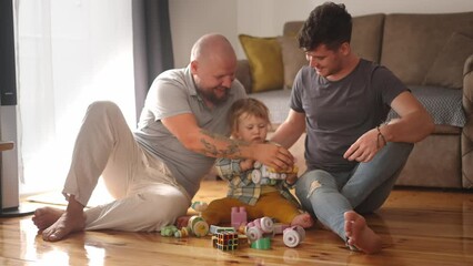 Authentic shot of young happy homosexual male gay family with adopted son toddler baby boyplay together