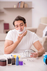 Young man shaving face at home