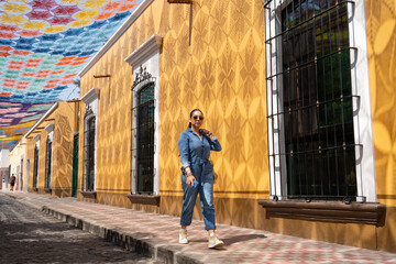 La joven está caminando por una calle del casco histórico de Etzatlán que tiene el Cielo Tejido más famoso del mundo.
