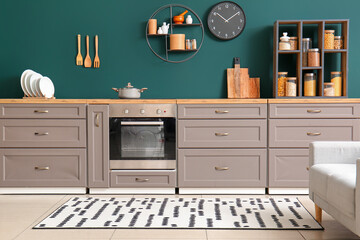 Interior of modern kitchen with grey counters, oven and stylish rug - obrazy, fototapety, plakaty