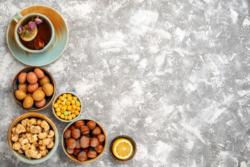 Obraz na płótnie Canvas top view cup of tea with nuts and candies on white background nut tea candy snack