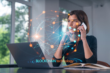 Pensive attractive beautiful businesswoman in formal wear working on laptop at office workplace in background. Using phone. Concept of business education, blockchain cryptocurrency technology.