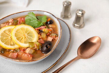 Bowl of tasty Hodgepodge soup on light background, closeup