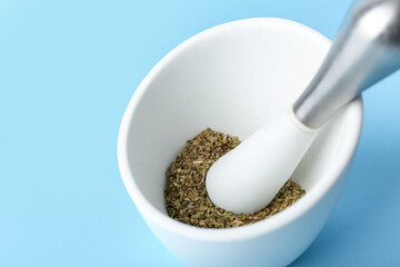 Mortar and pestle with spices on blue background, closeup