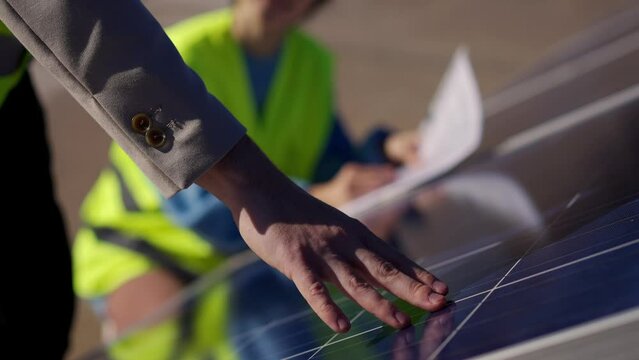 Close up of young engineer hand is checking the operation of sun and cleanliness of photovoltaic solar panels on a sunset. Concept.renewable energy, technology, electricity, service, green, future.