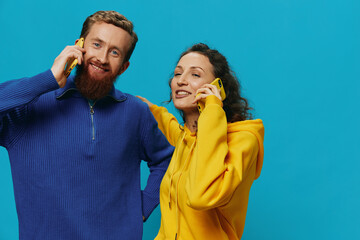 Woman and man cheerful couple with phones in their hands crooked smile cheerful, on blue background. The concept of real family relationships, talking on the phone, work online.