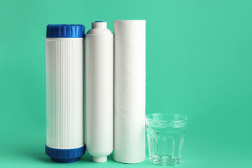 Glass of liquid and water filter cartridges on green background