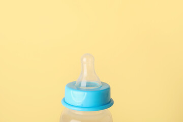 Bottle with milk for baby on pale yellow background