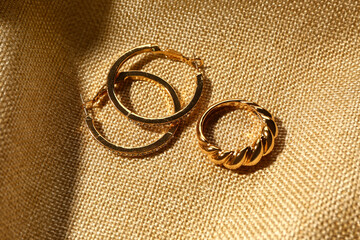 Beautiful earrings and ring on beige fabric background