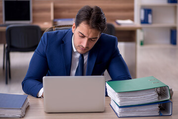 Young male employee and too much work in the office