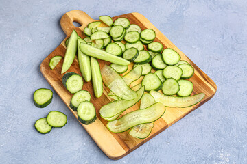 Wooden board with fresh cut cucumber on grey background