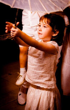 A cute little girl holding a paper umbrella at a white clothes party