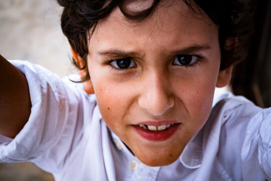 A boy looking directly at the camera with an intense look on his face.