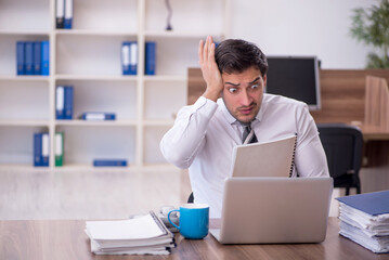 Young male employee unhappy with excessive work at workplace