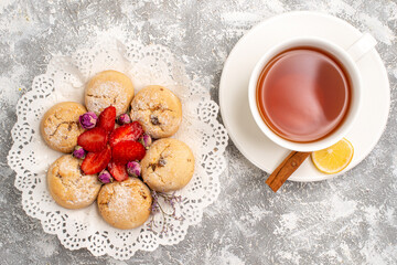 top view delicious sand cookies with fresh strawberries and cup of tea on light white background fruit berry biscuit sugar cookie sweet
